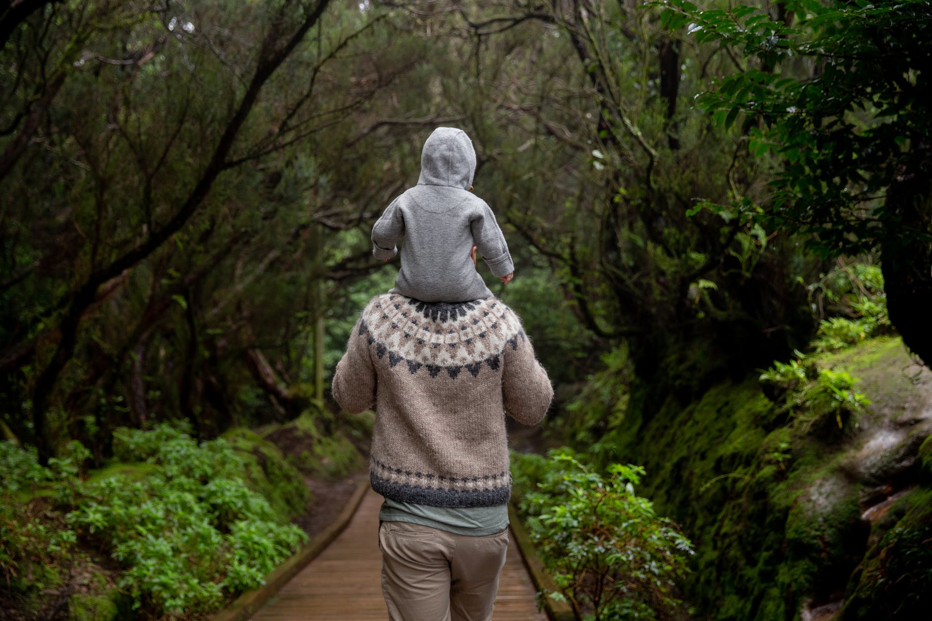 anonymous man with baby on shoulders walking away