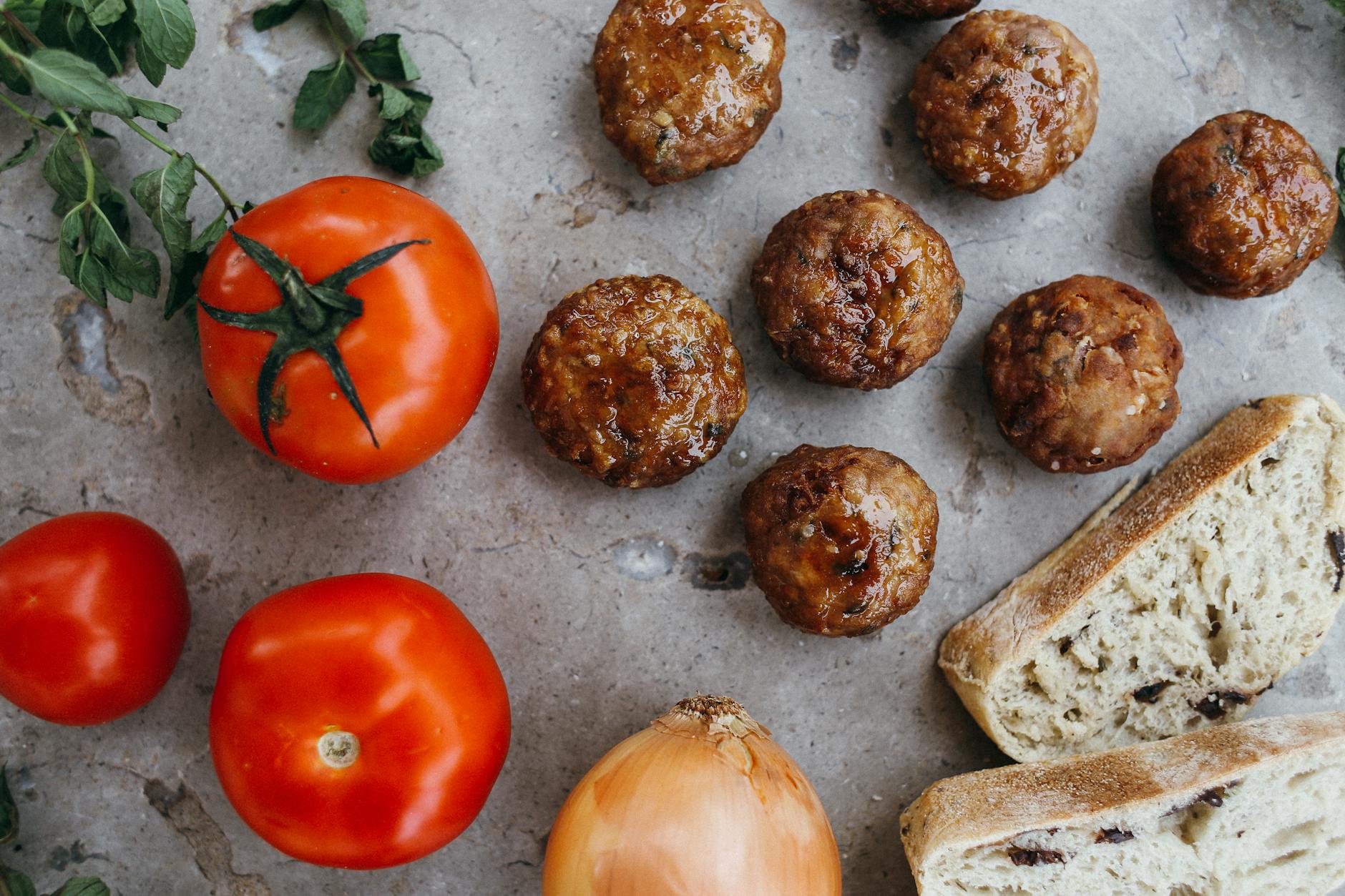 red tomatoes beside a sliced bread meatballs